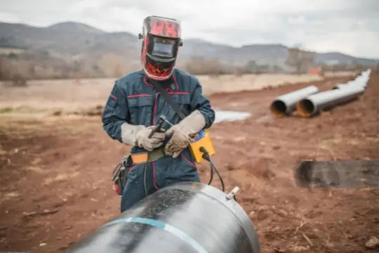 A welder is welding pipes outside